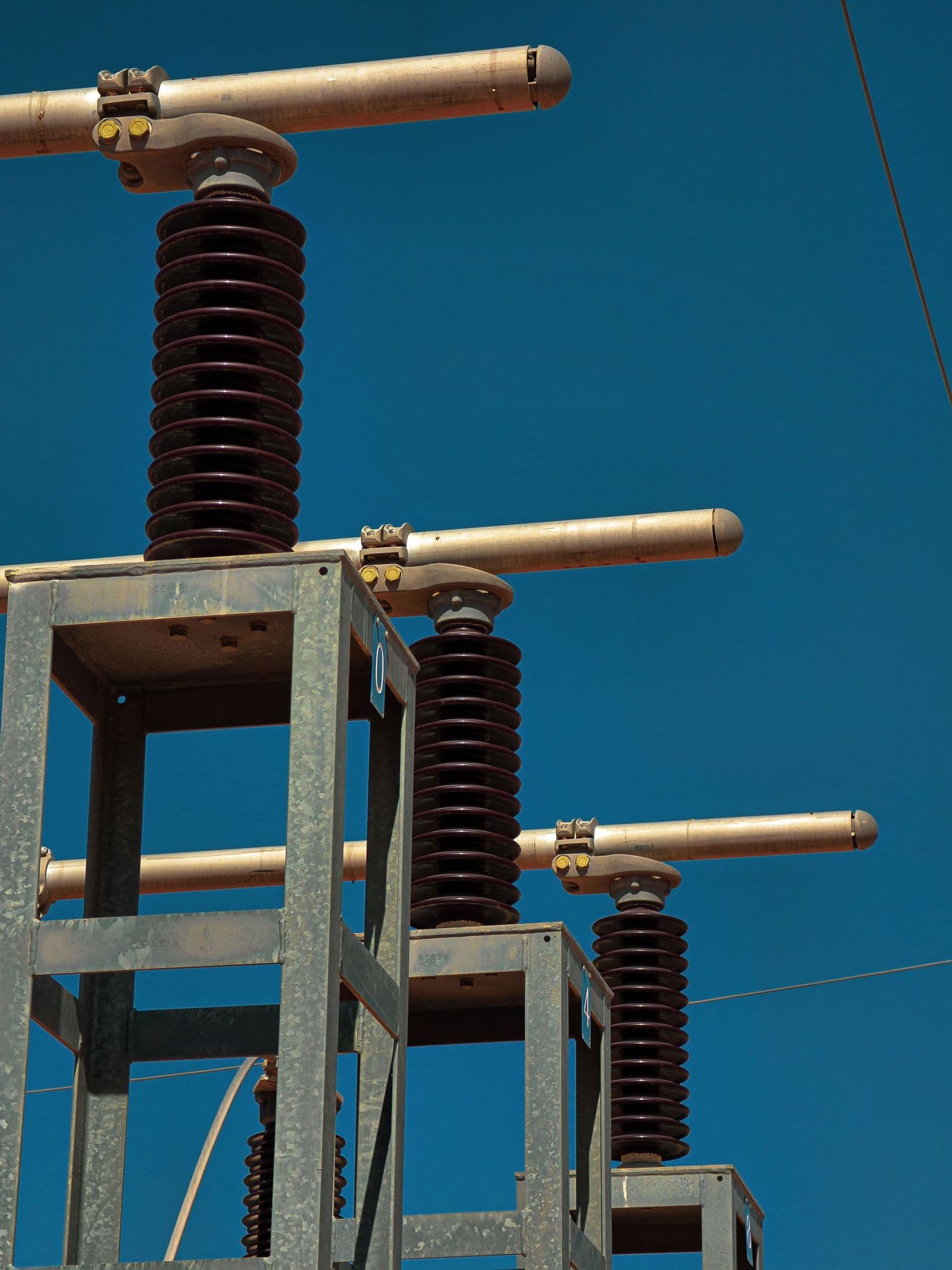Insulators and bus clamps on a substation disconnect against a blue sky