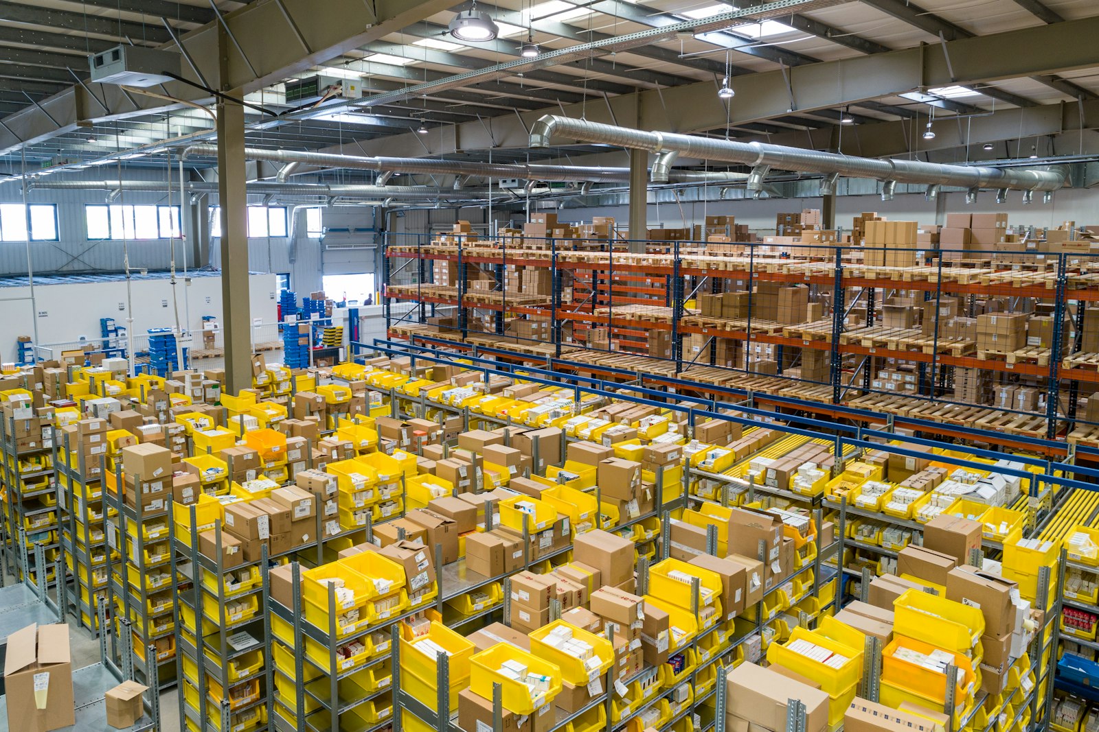 Parts warehouse with rows of stocked yellow bins and boxes